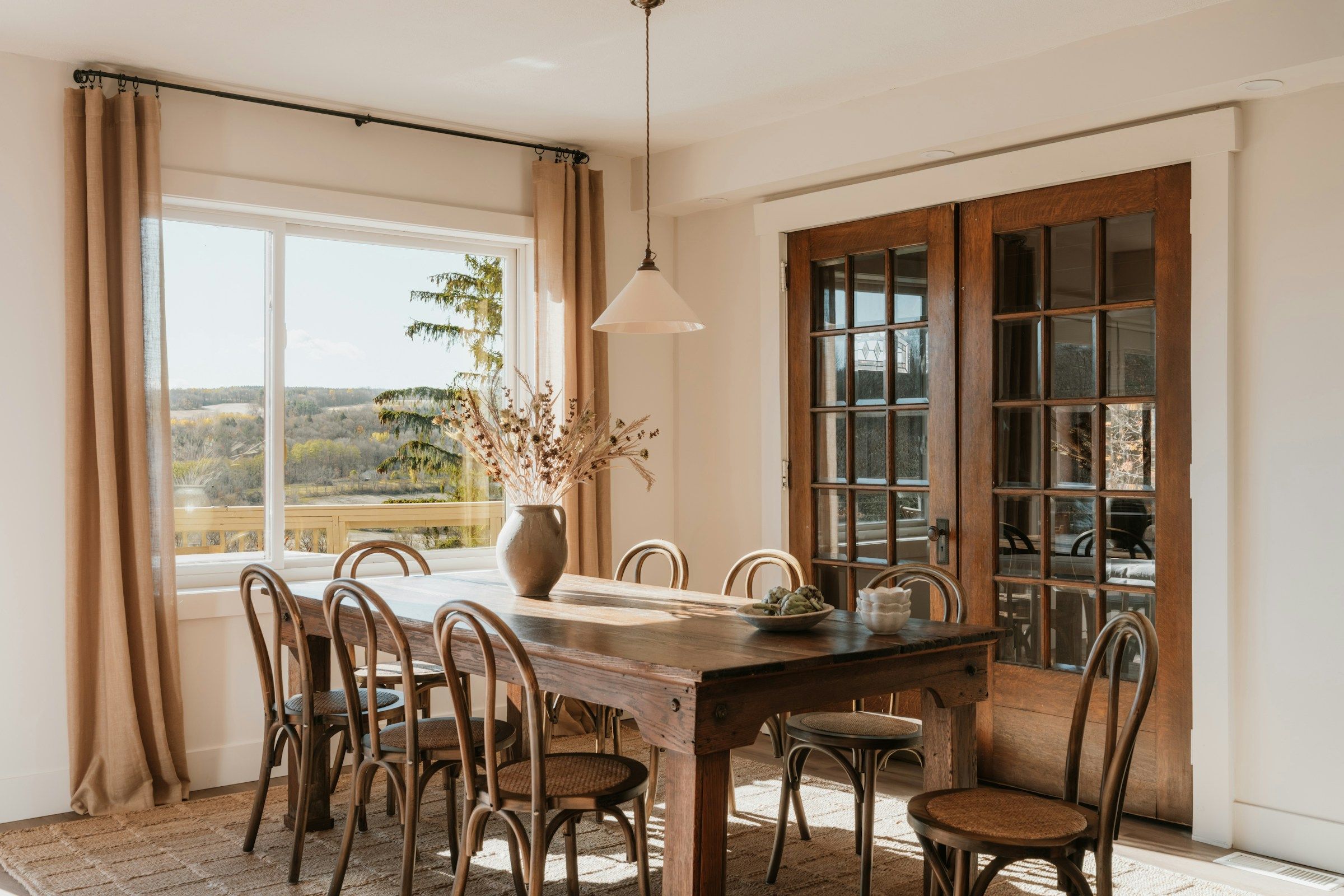 Esszimmer mit massivem Holztisch, Fenster und Flügeltür aus Holz